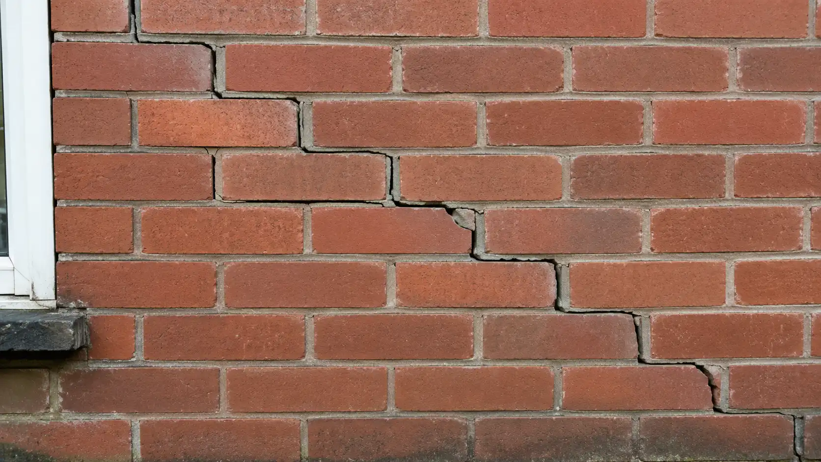 Architecte examinant des fissures sur un mur béton armé lors d'une inspection structurelle — RS Ingénierie